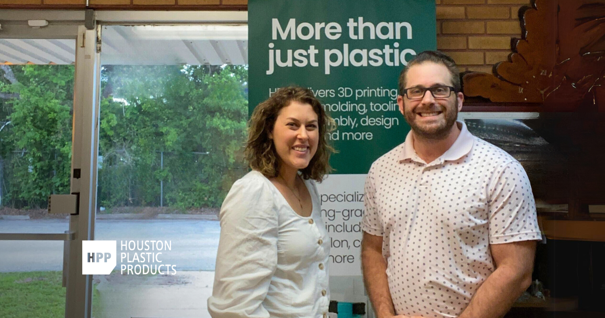 Katelyn Strumolo and Andrew Wooley (President of HPP) stand in front of an HPP banner that reads 'More than just plastic,' showcasing the company's services. This banner is just one of the ways we helped HPP reimagine all of their print marketing materials, resulting in better sales and marketing tactics.